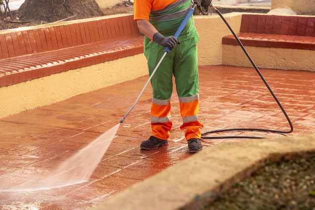 Worker cleaning the streets with a pressurized bleach water gun