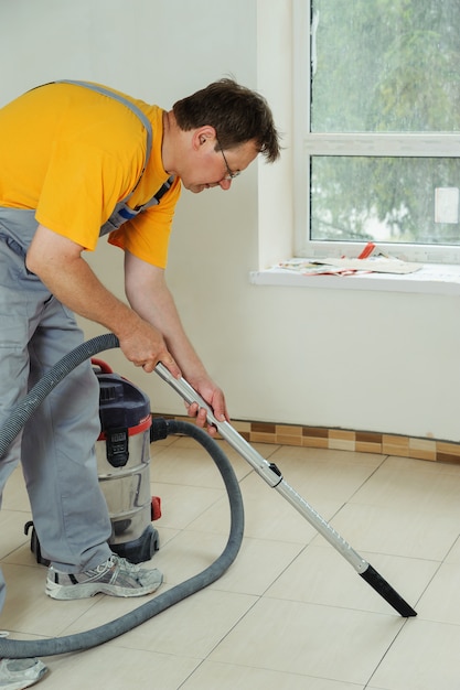 Foto il lavoratore pulisce le cuciture tra le piastrelle