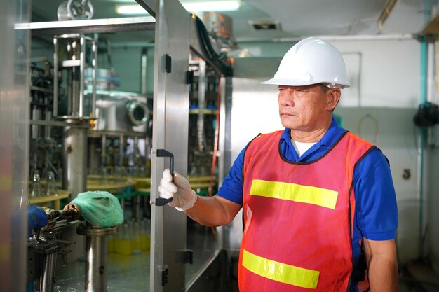 Worker controlling the work of machine in production line at beverage industry