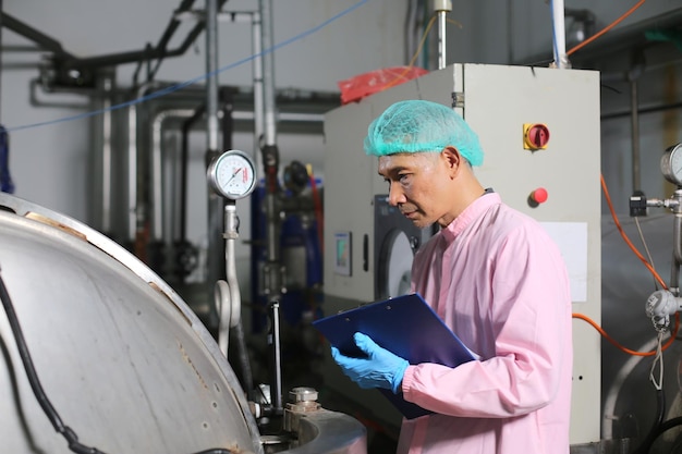 Worker controlling the work of machine in production line at beverage industry