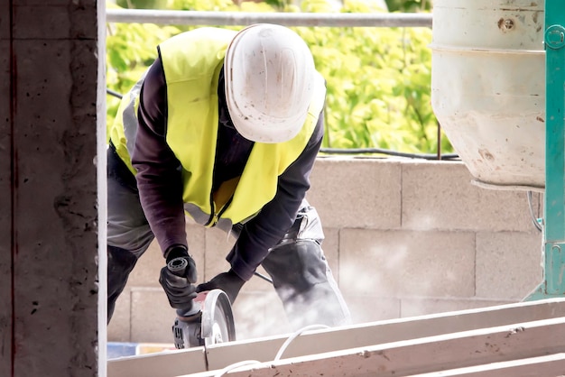 Фото Рабочий режет конструкцию с помощью круговой машины, поднимающей пыль рядом с бетонным смесителем на балконе