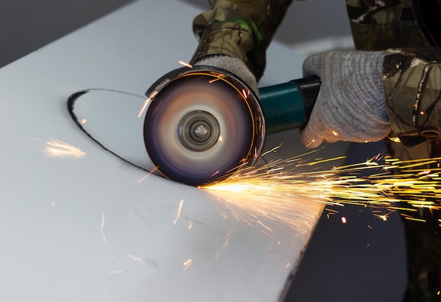 Photo a worker cuts a circle in metal with an angle grinder