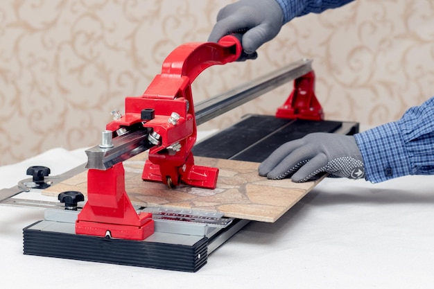 A worker cuts facing tiles with a tile cutter