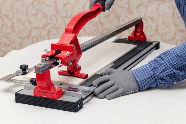 A worker cuts facing tiles with a tile cutter