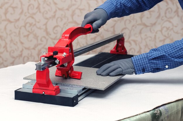 A worker cuts facing tiles with a tile cutter