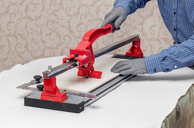 A worker cuts facing tiles with a tile cutter