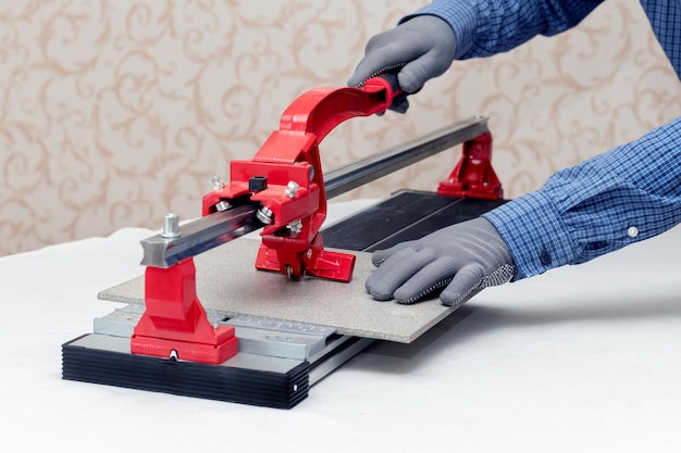 A worker cuts facing tiles with a tile cutter