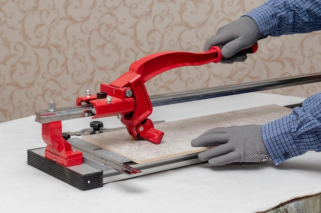 A worker cuts facing tiles with a tile cutter