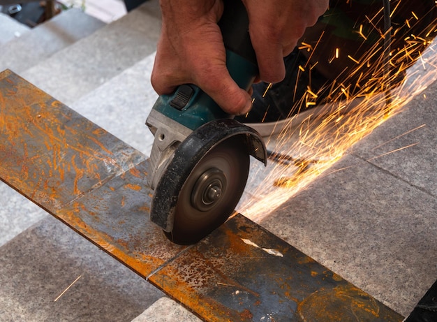 a worker cuts a metal sheet with an angle grinder