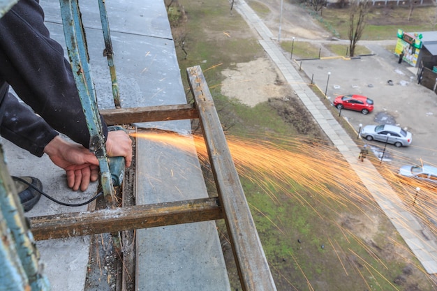 A worker cuts metal with a grinder