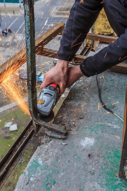 A worker cuts metal with a grinder