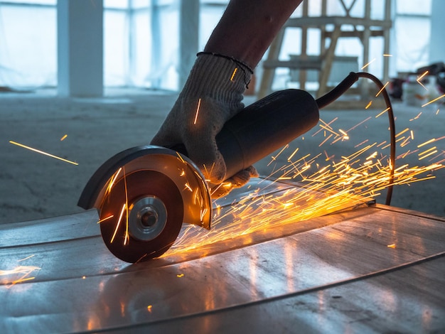 Photo worker cuts a metal workpiece with an angle grinder