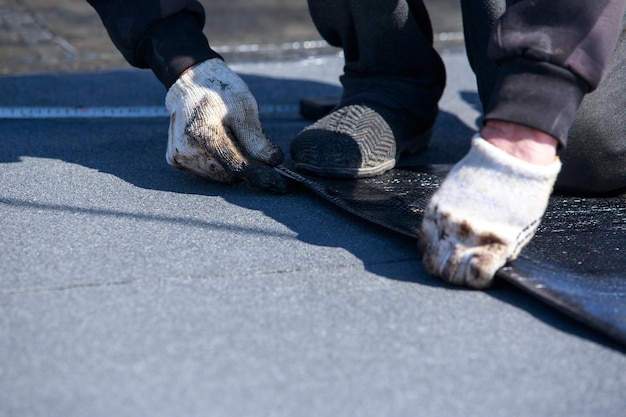 worker cuts roofing material