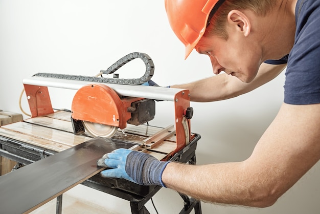 Worker cutting a ceramic tile on a wet cutter saw  machine