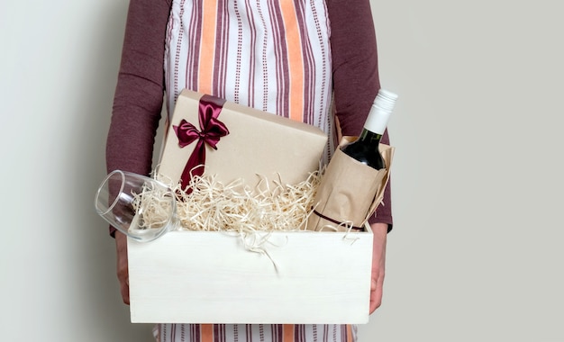 Сотрудник службы доставки упаковка бутылки вина и подарков в коробку с соломинкой для клиента.