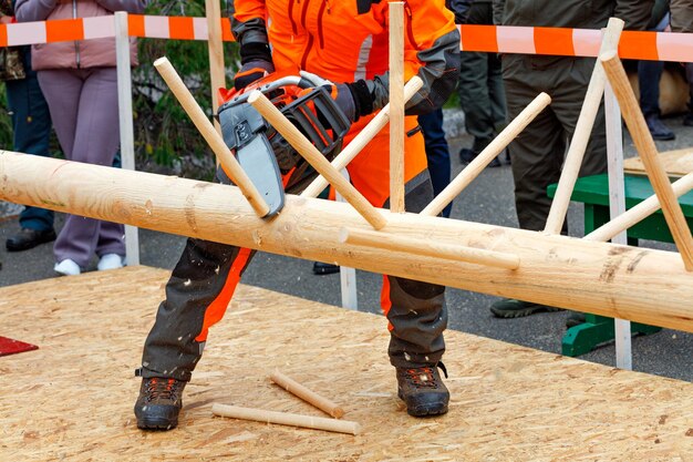 Photo a worker demonstrates the skill of using chainsaw at the working site of the lumberjack competition