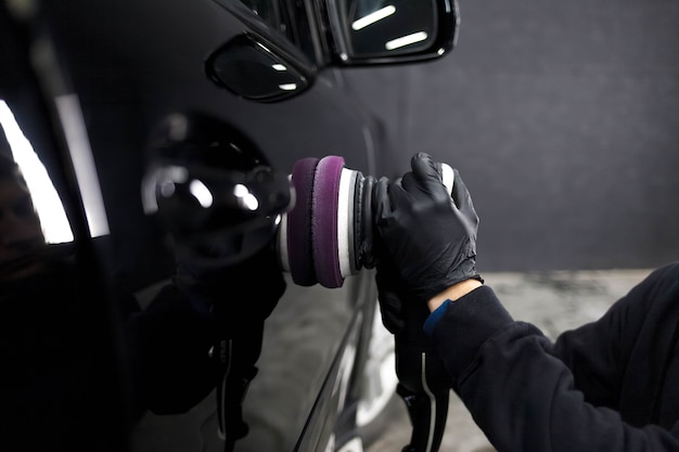 Worker of the detailing center polishes car body