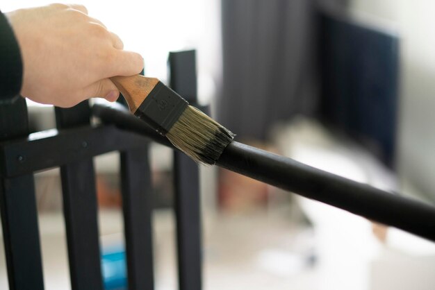 A worker doing painting job with black color using brush