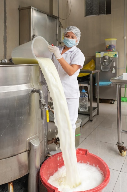 Worker emptying milk from a tank to a pot in a dairy industry