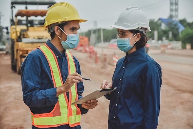 Worker Engineer wear mask working by tablet on site road construction