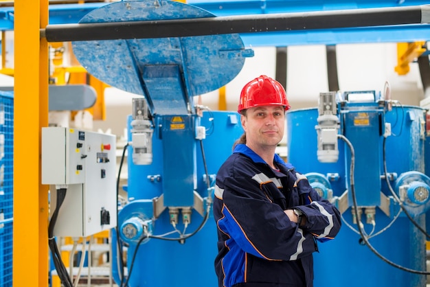 Worker in a factory looking at camera with machines in the background