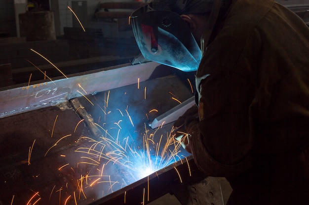 Lavoratore al primo piano di saldatura di fabbrica scintille industriali