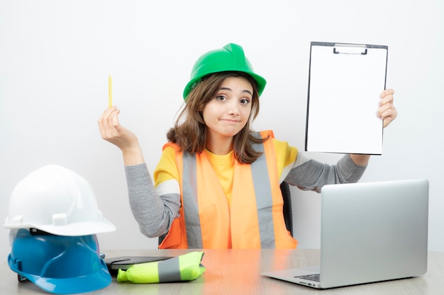 Worker female in uniform sitting at the desk with laptop and clipboard . High quality photo