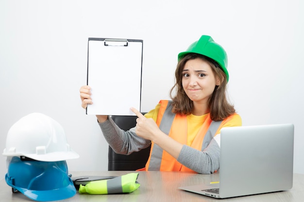 Worker female in uniform sitting at the desk with laptop and clipboard . High quality photo