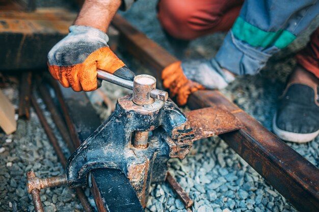 Worker fixes a metal part in a vise before cutting