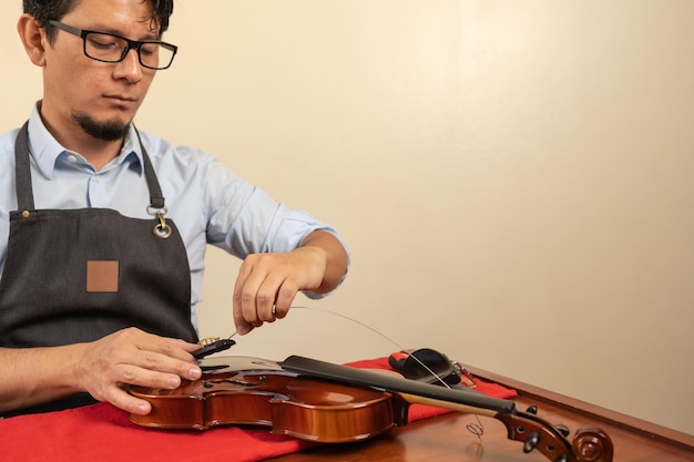 Worker fixing the strings of a violin in a workshop