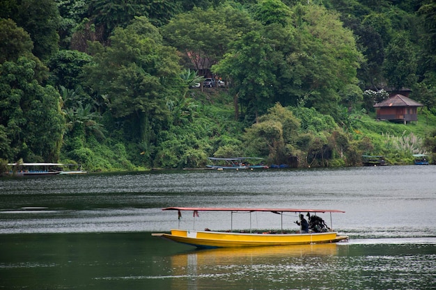 Рабочий гид, местные жители, плывущие на деревянной длиннохвостой лодке, привозят тайских и иностранных путешественников в тур для посещения плотины Кхун Дан Пракан Чон или плотины Клонг ТхаДан в Накхон Найок, Таиланд.