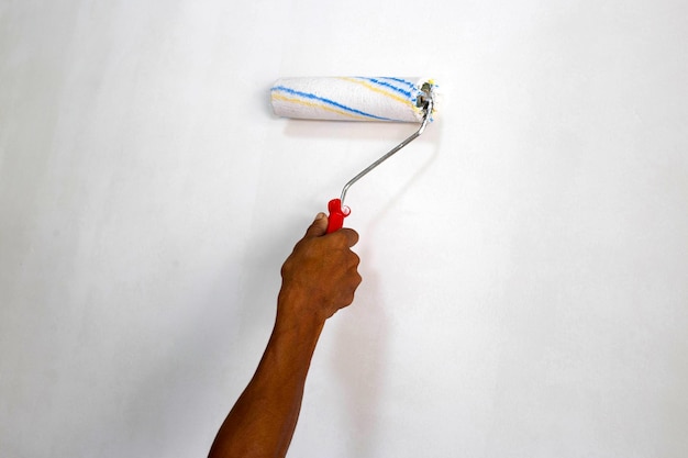 Worker hand hold paint roller Painting a wall