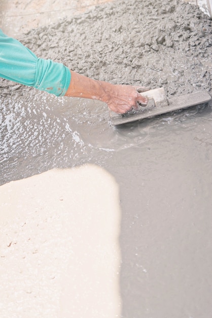 worker hand with trowel leveling concrete.