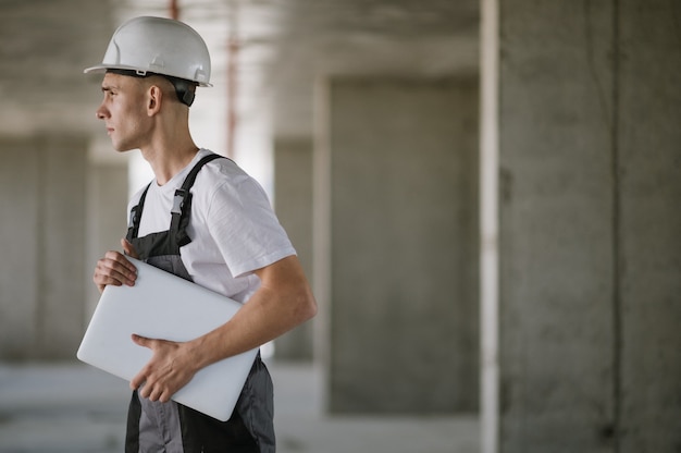 Lavoratore in elmetto che lavora al computer portatile