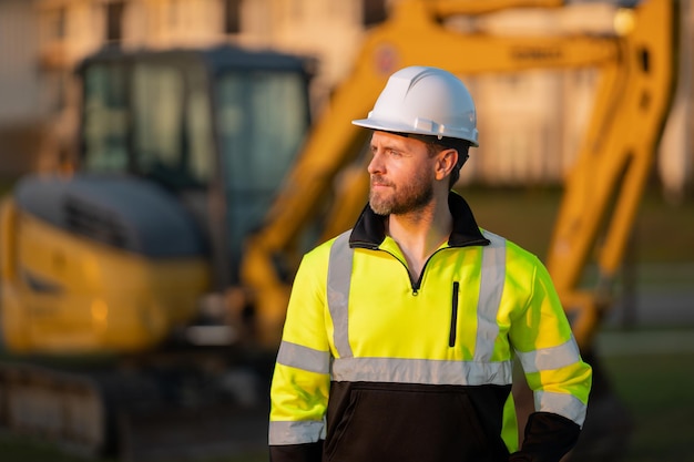 Worker in helmet on site construction excavator bulldozer male worker construction driver worker wit