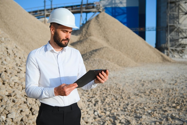 a worker in a helmet stands at a stone crushing plant