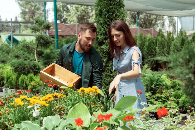 Worker helping female customer with plant in garden center