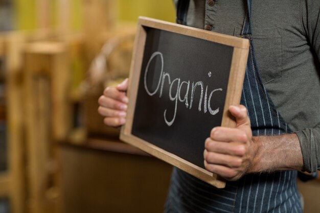 Photo worker holding a board with organic sign at grocery store