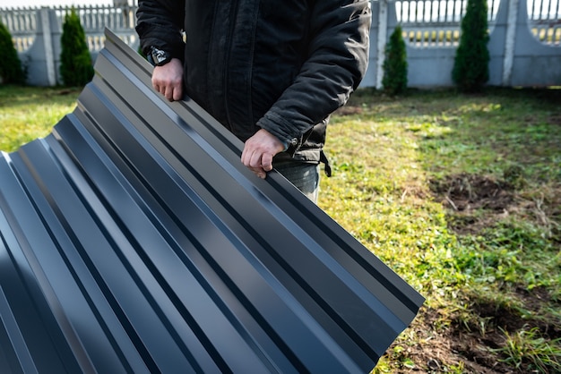 Worker holding metal sheet on grass background