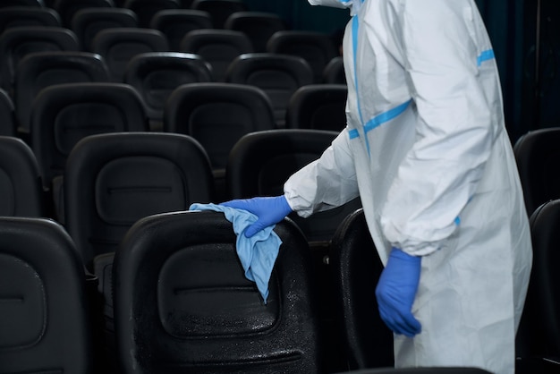Worker holding rag and wiping chairs in cinema