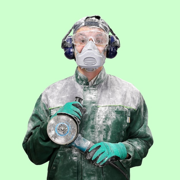 Фото Рабочий в защитной одежде стоит с рабочим инструментом в руках весь в белой пыли