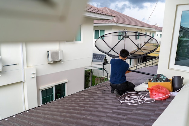 작업자가 집 지붕에 디지털 TV 위성 접시를 설치하고 설정합니다.