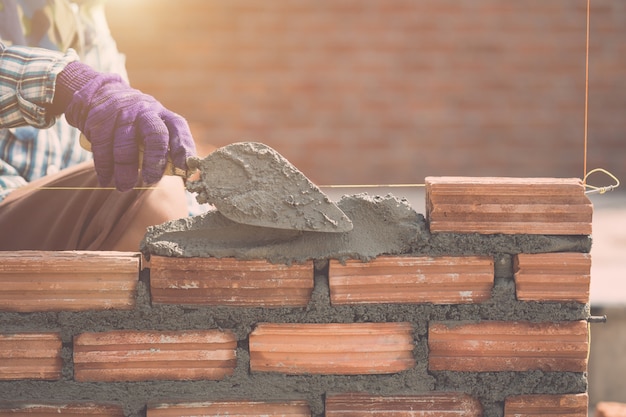 Worker installing bricks wall in process of house building