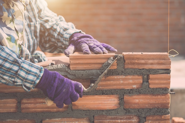 Worker installing bricks wall in process of house building