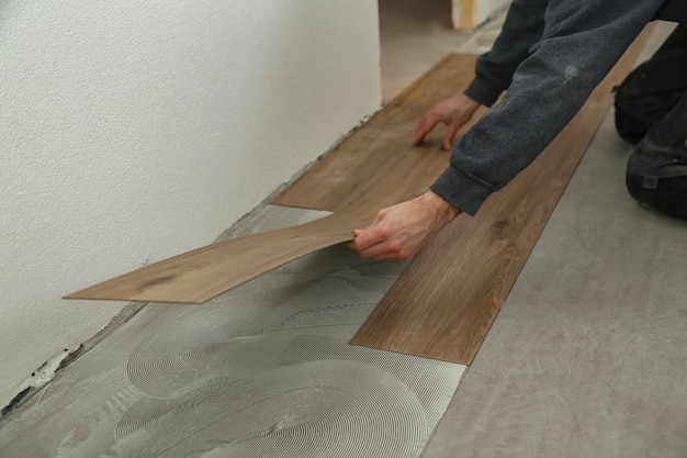 Worker installing the new vinyl tiles on the floor in the house