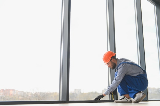 Worker installing plastic window indoors