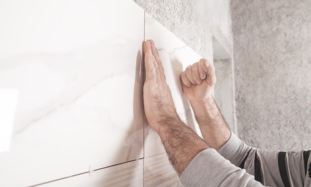 Lavoratore che installa piastrelle sul muro.