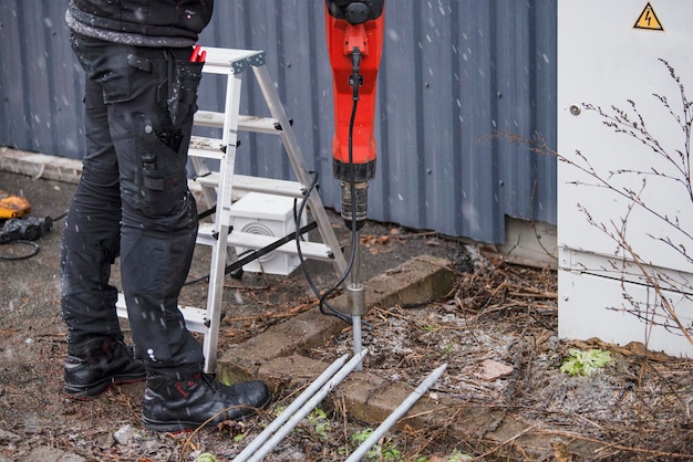 Foto un operaio installa un picchetto di terra per mettere a terra un edificio in cui un operaio in abiti da lavoro inserisce dei picchetti di terra