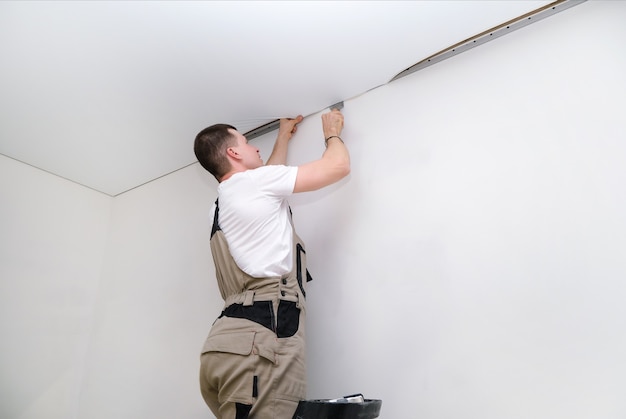 Il lavoratore installa un soffitto teso. concetto di costruzione e ristrutturazione