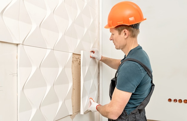 The worker is attaching the gypsum tile to the wall